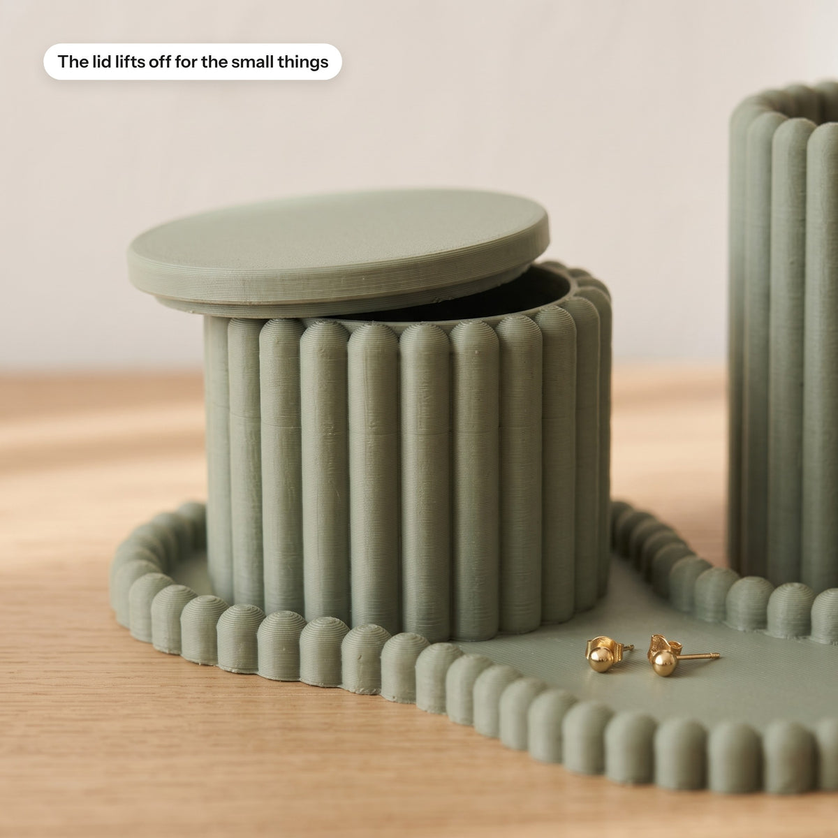 Close-up of the ribbed lidded pot with the lid lifted and earrings in the tray