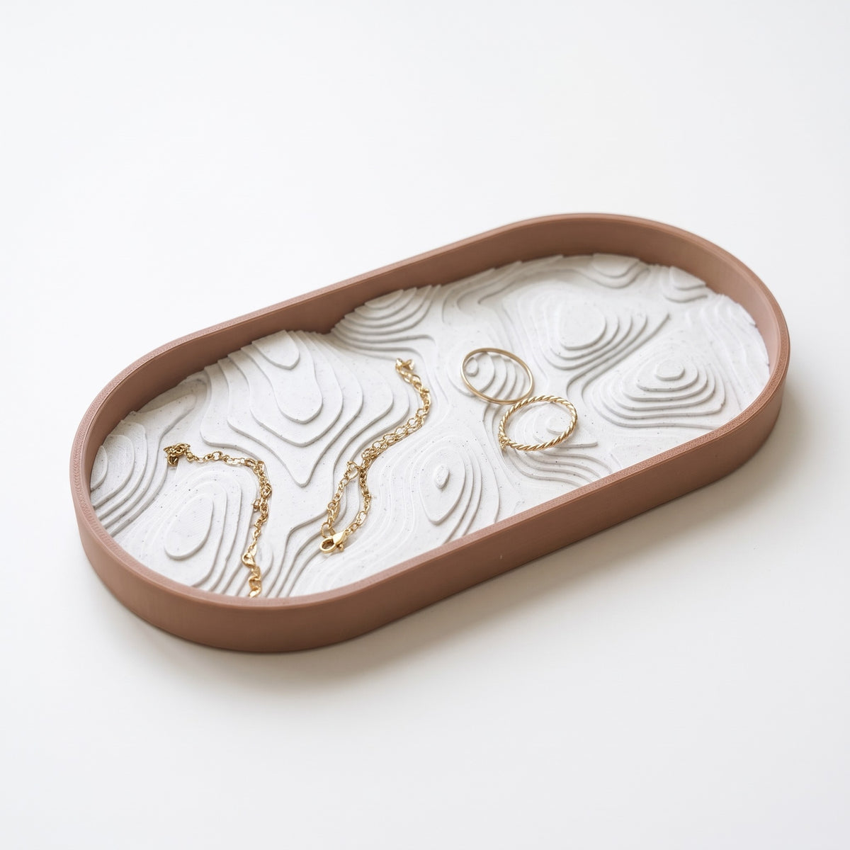 Topo oval jewelry tray holding gold rings and a chain