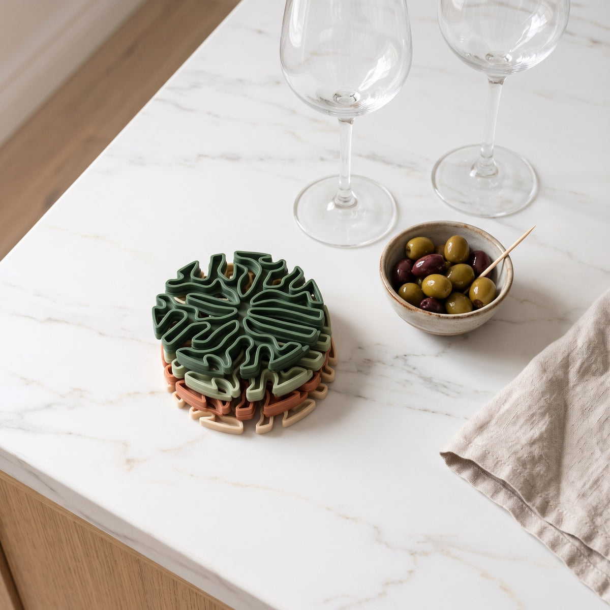Stack of four coasters on a kitchen counter with wine glasses